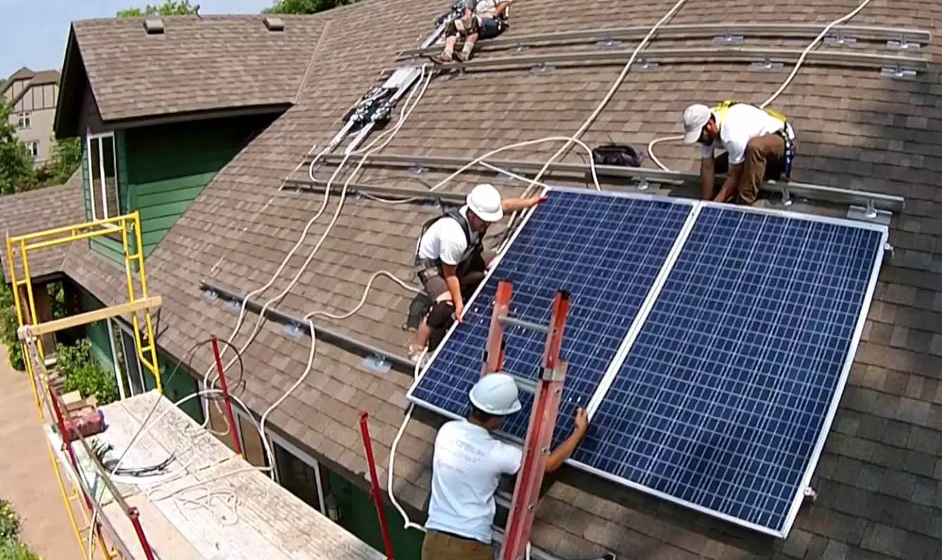 a group of men installing solar panels on a roof