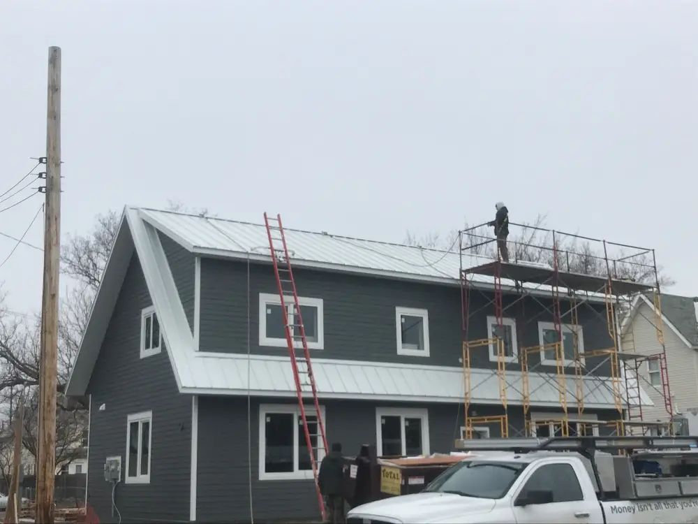 a man on a scaffolding next to a house