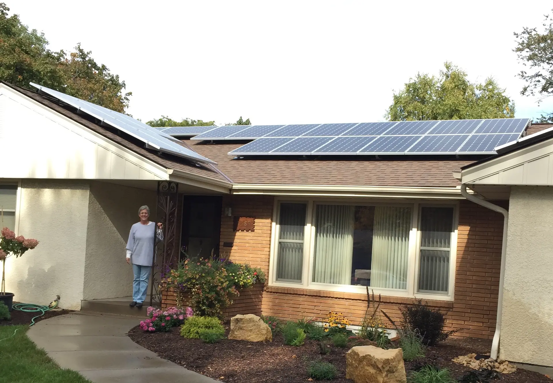 a woman standing in front of a house with solar panels on the roof