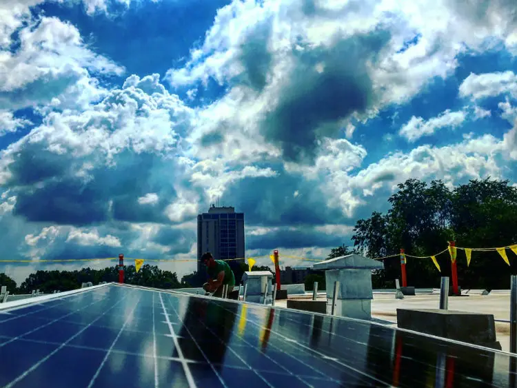 a man standing on a roof with solar panels