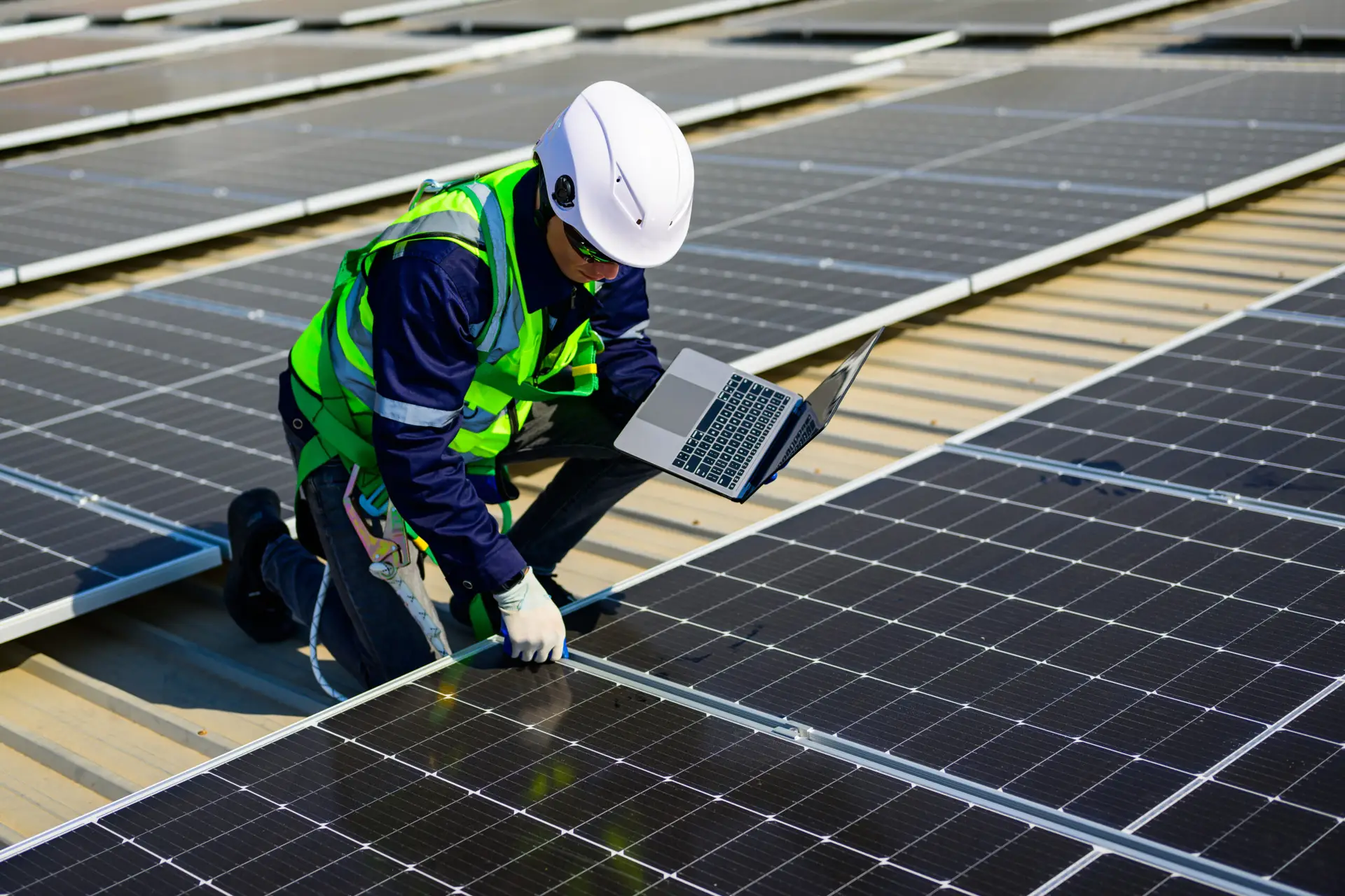 a man in a reflective vest and white helmet working on a solar panel