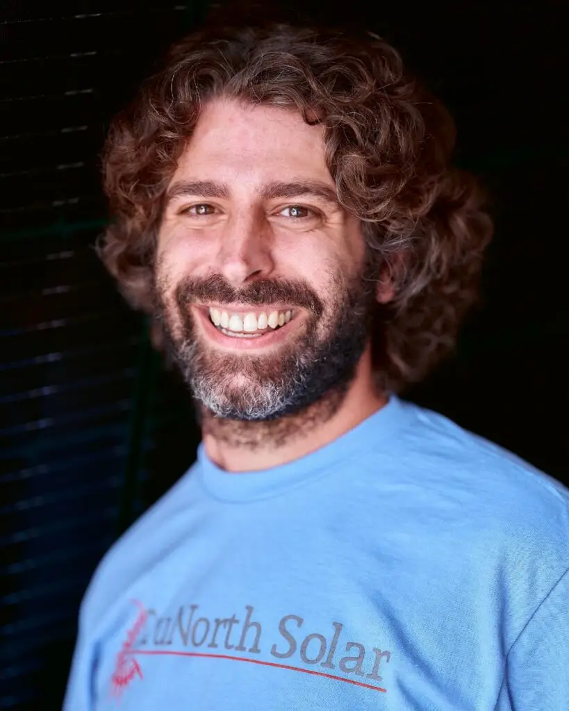 a man with curly hair and beard smiling