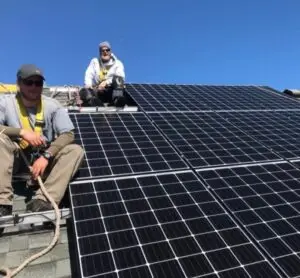 a group of men on a roof with solar panels