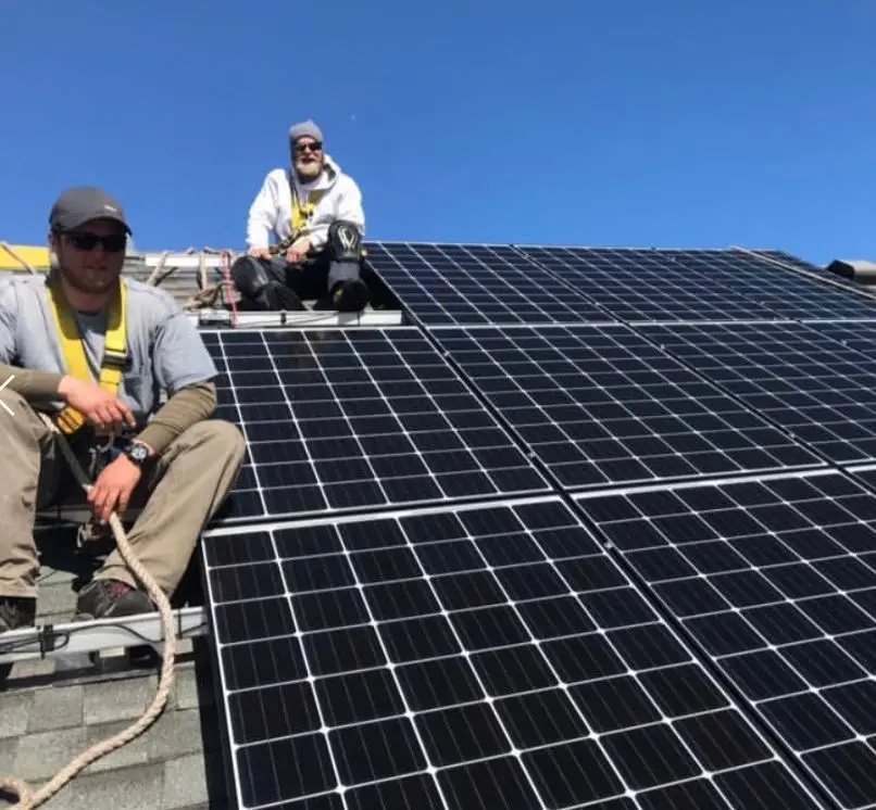 a group of men on a roof with solar panels