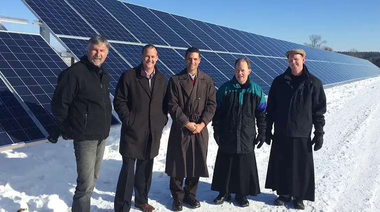 a group of men standing in front of solar panels